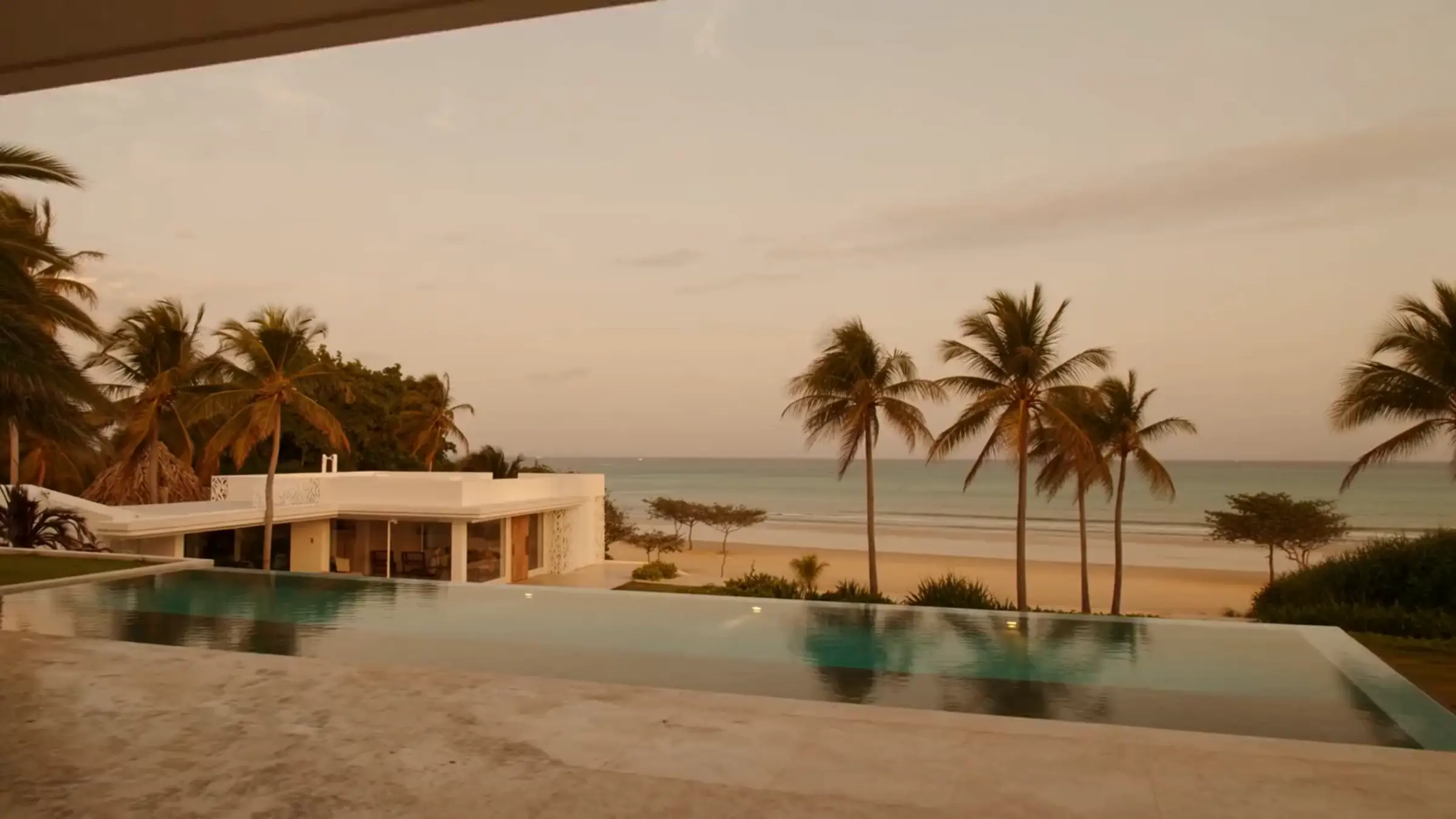 Villa moderna con piscina infinita frente al mar al atardecer