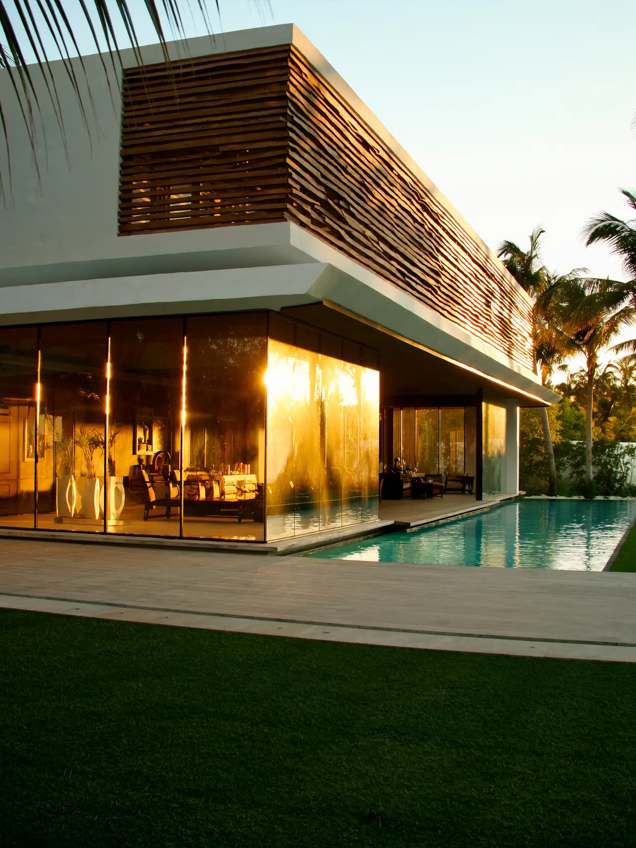 A modern villa at sunset with a pool and palm trees